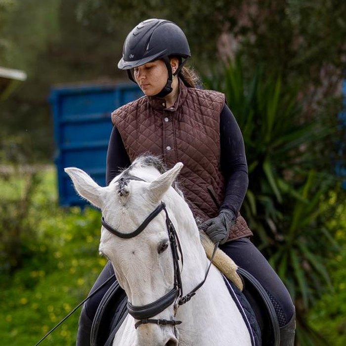 Maria de Santiago Abecasis riding a grey horse during a lesson in the arena