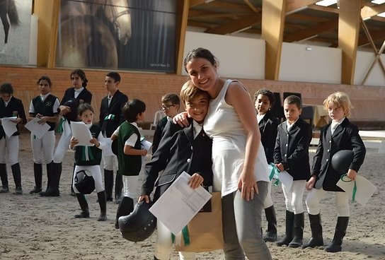 L'un des plus jeunes de la famille serrant la monitrice dans ses bras, un jour d'examen d'équitation avec d'autres enfants